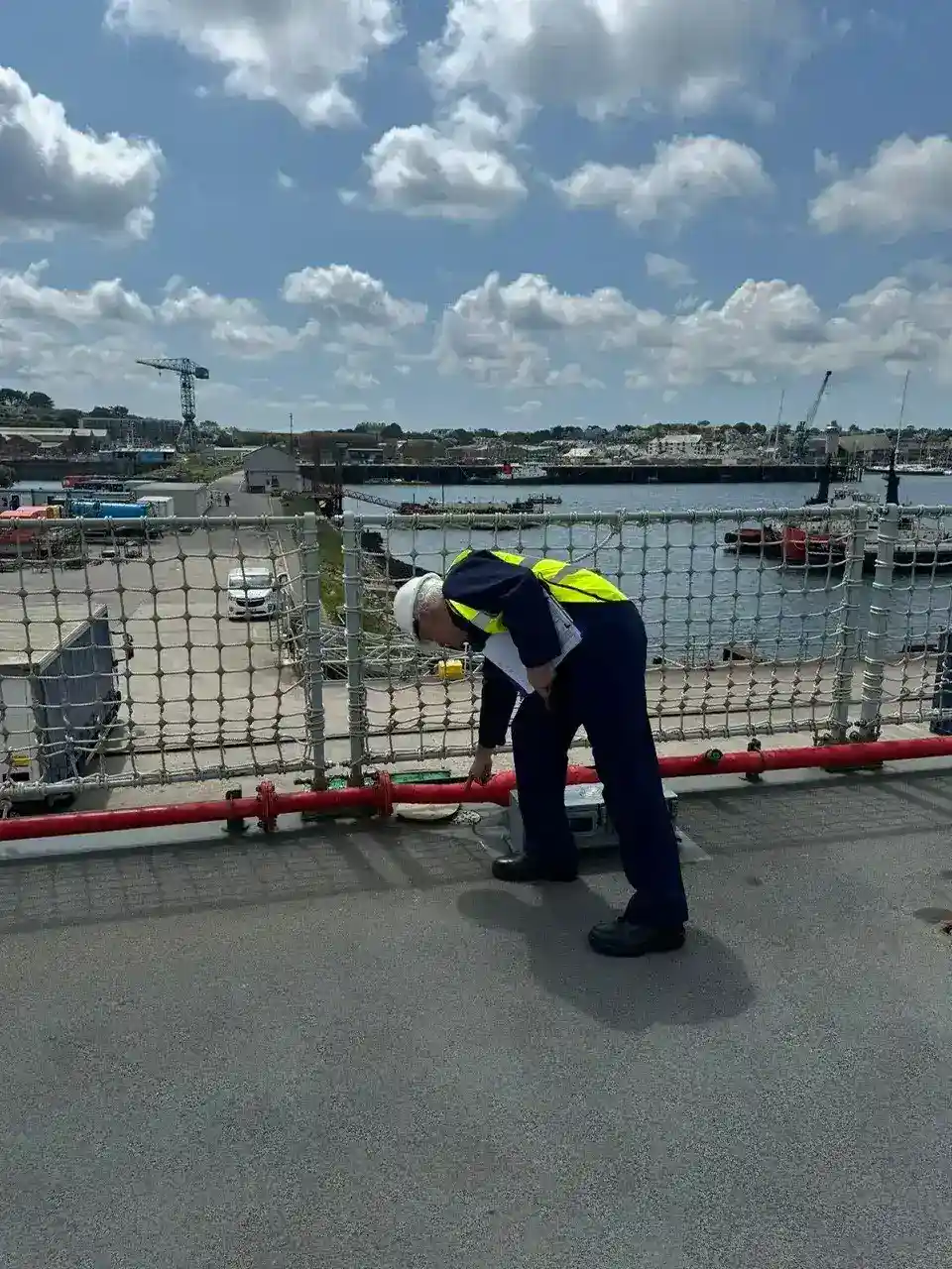 A worker checking pipes and equipment on a ship's deck.