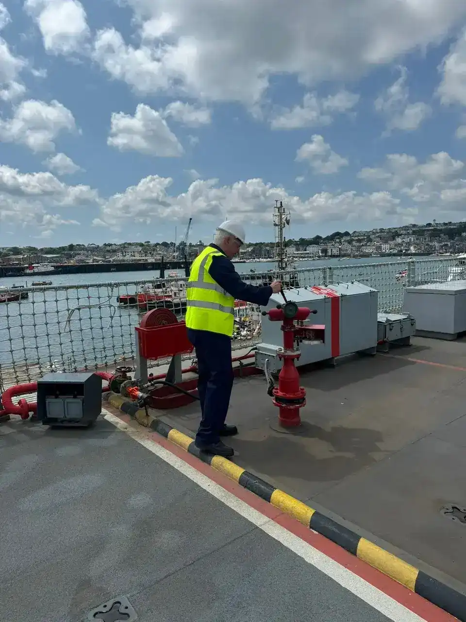 A man working maritime equipment on a ship's deck.