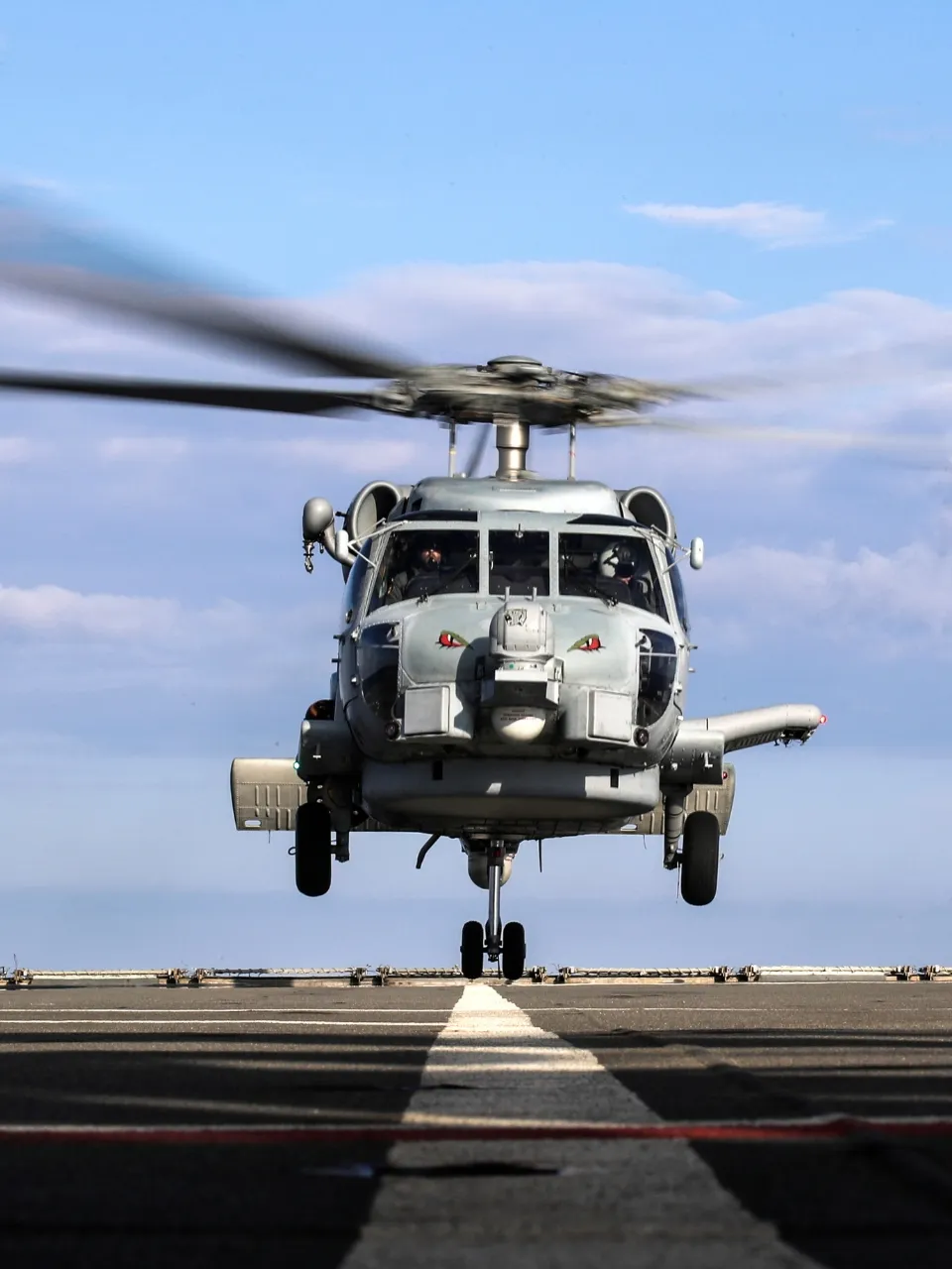 A military helicopter on a run way, getting ready to take off.