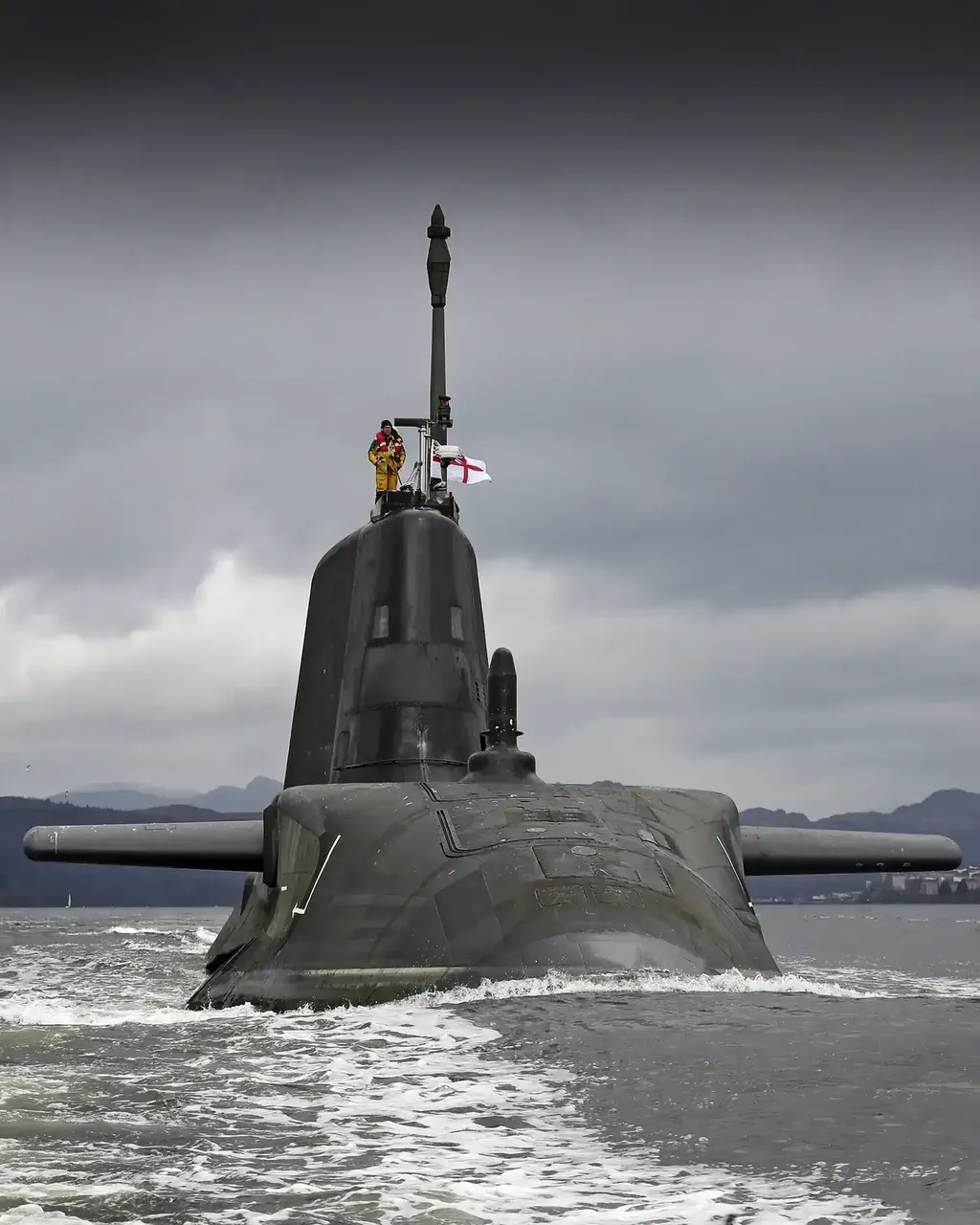 A surfaced submarine with a crew member stood on the top of it.