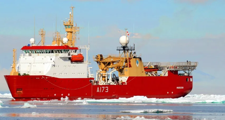 An expedition ship sailing through the sea, with ice and snow around it.