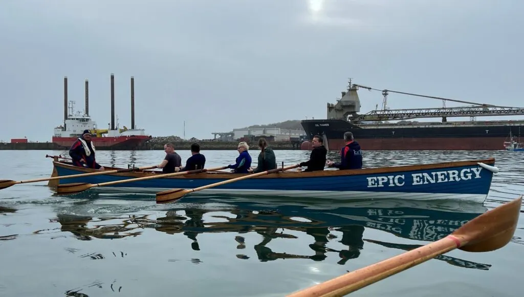 An old rowing boat with a crew rowing through the water.