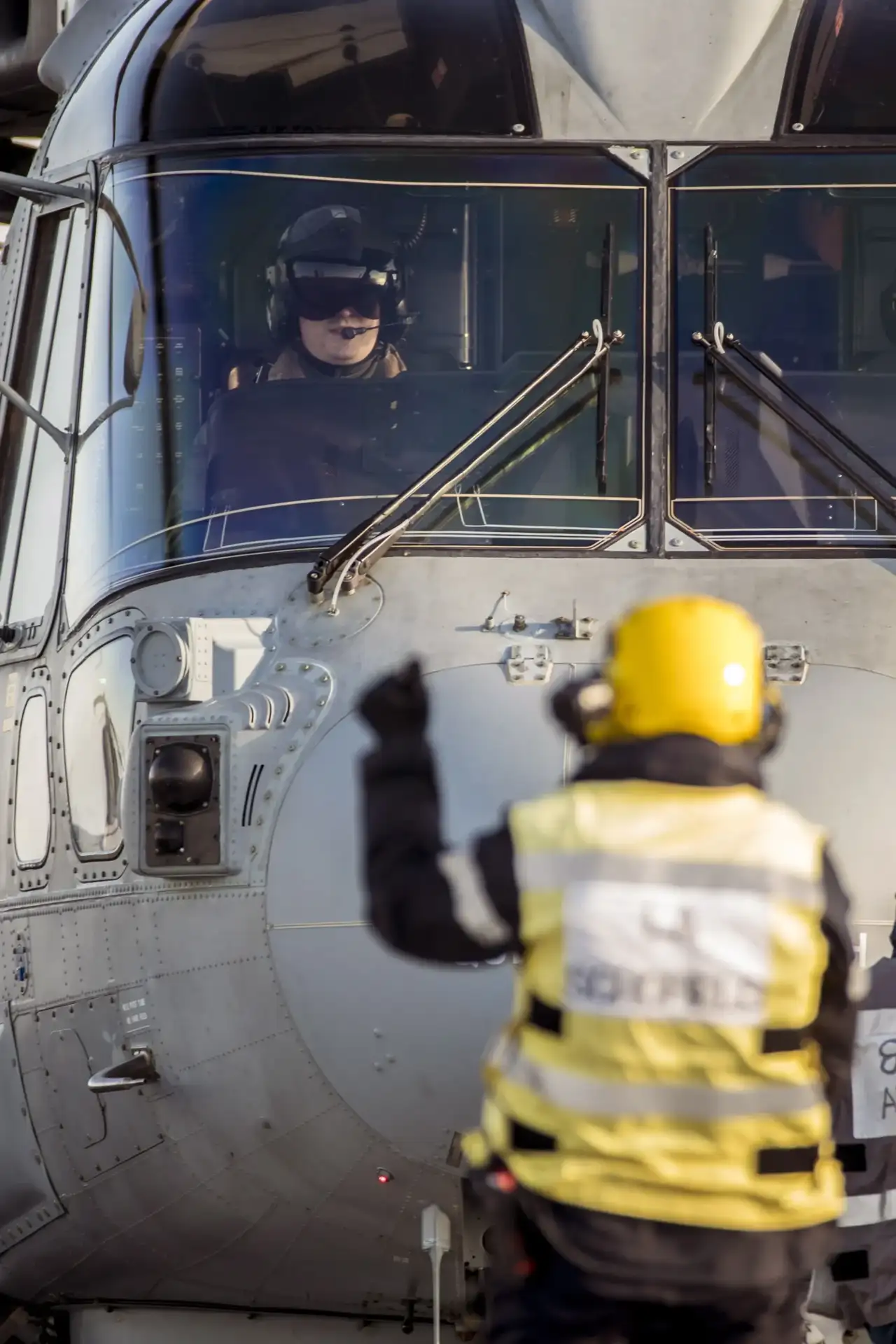 An operator guiding a helicopter on an air field.