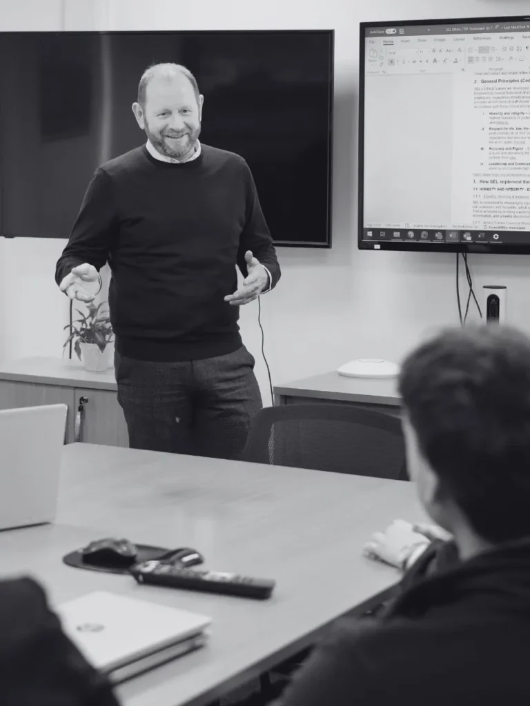 A man stood up giving a lecture about ship design.