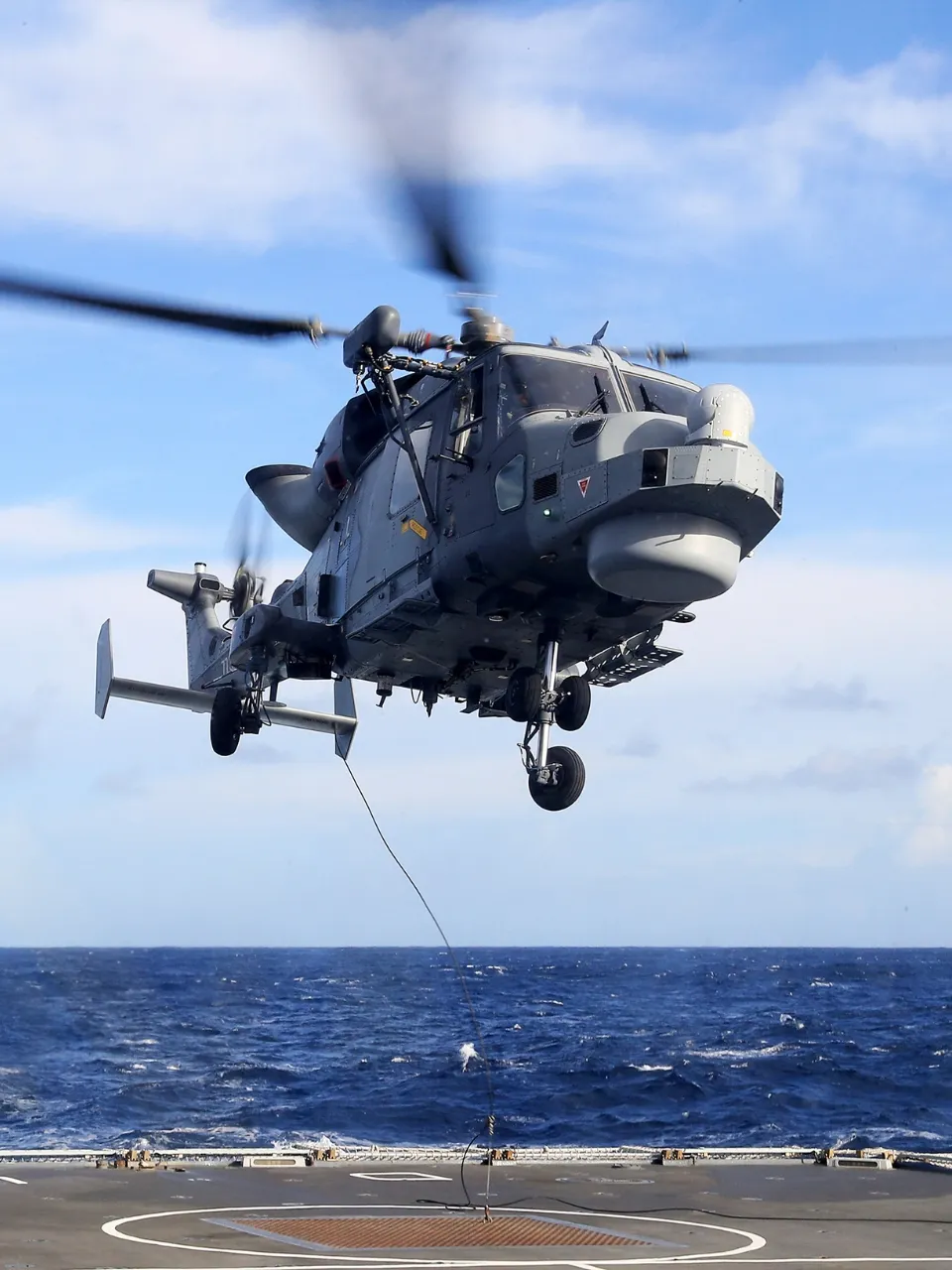 A military helicopter landing on a flight deck.