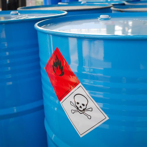 Blue barrels containing hazardous materials with warning stickers on them.